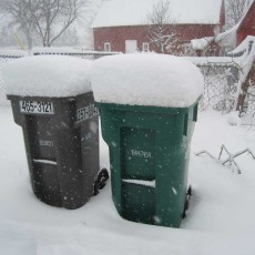 A foot of snow atop a garbage bin and a recycling bin.